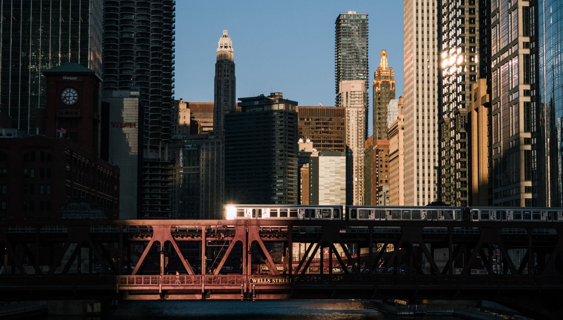 a train on a bridge over a river with buildings in the background