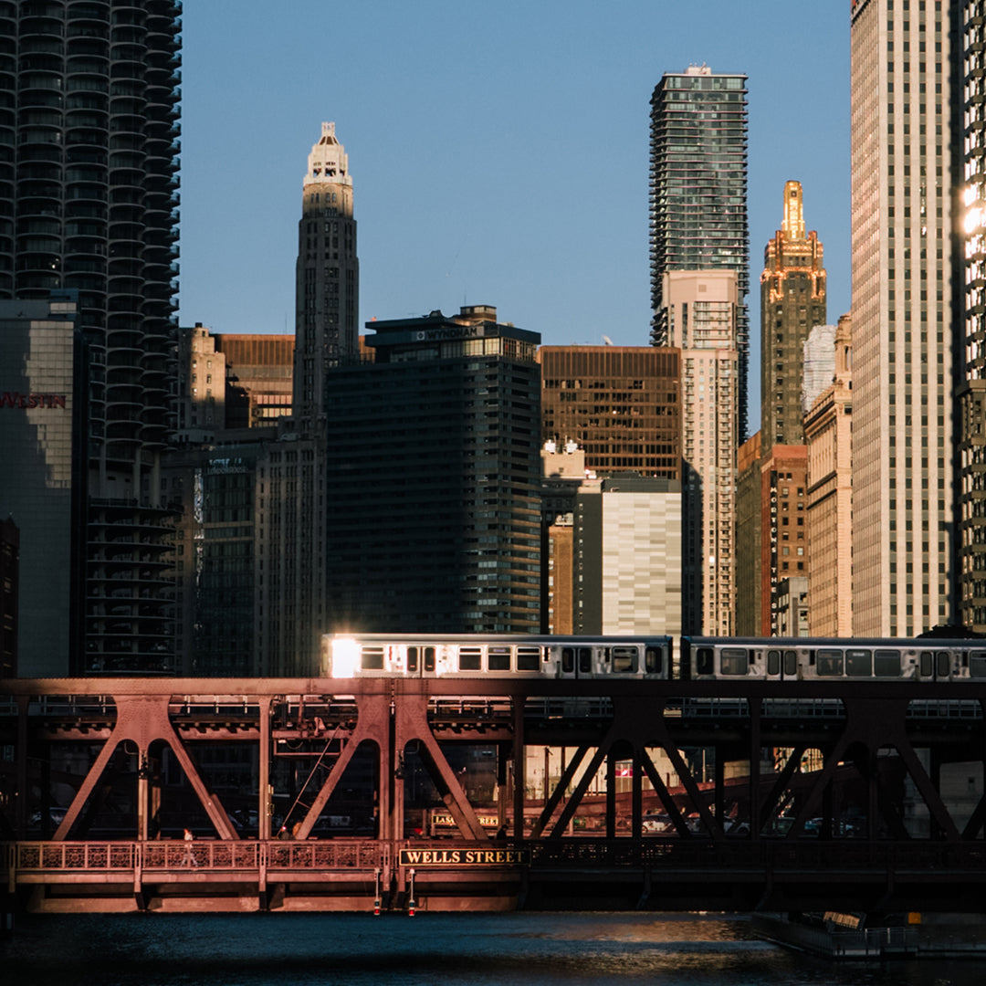a train on a bridge over a river with buildings in the background